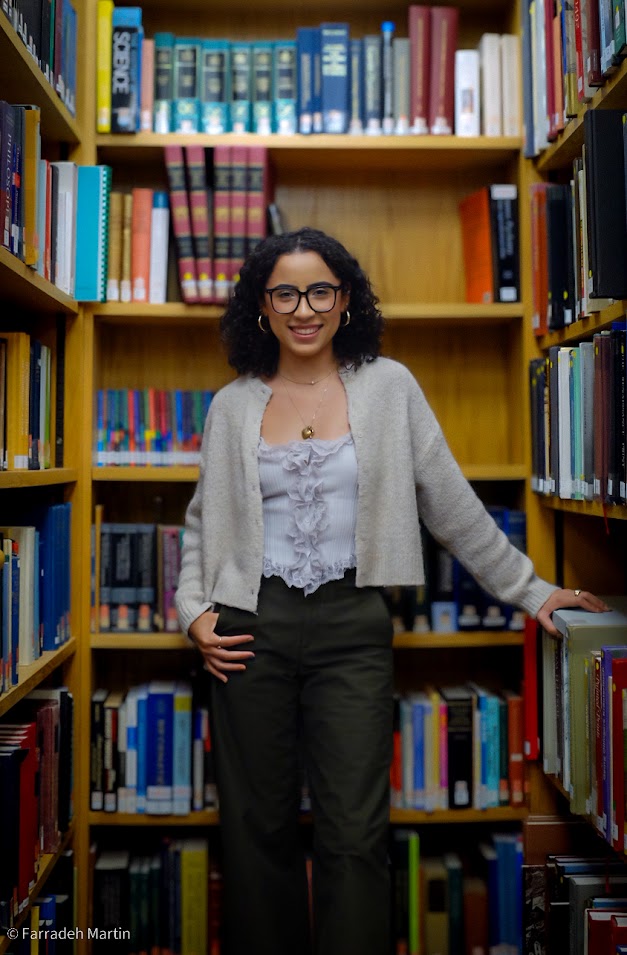 Portrait photo of Paulina Pimentel-Mora standing in the whipple library, leaning on a bookshelf