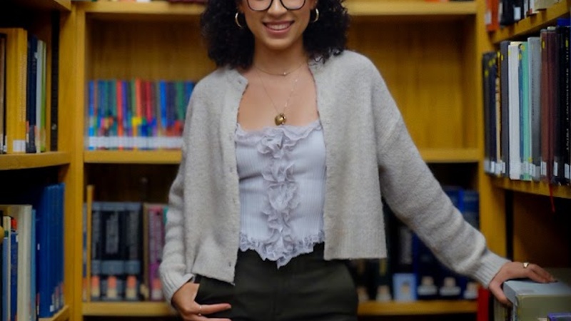 Portrait photo of Paulina Pimentel-Mora standing in the whipple library, leaning on a bookshelf