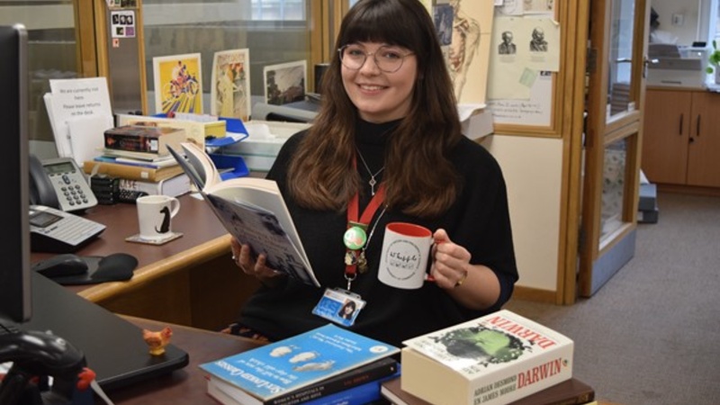 Liz White sat the the front desk, drinking tea and reading a book