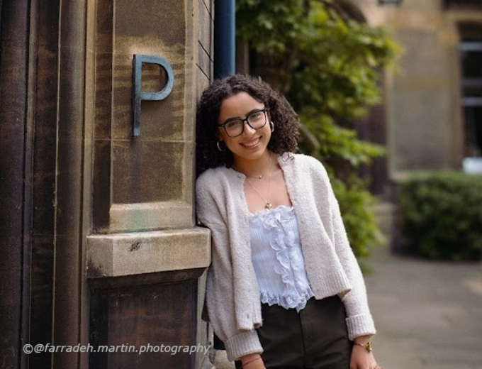 Female Student leaning on side of building