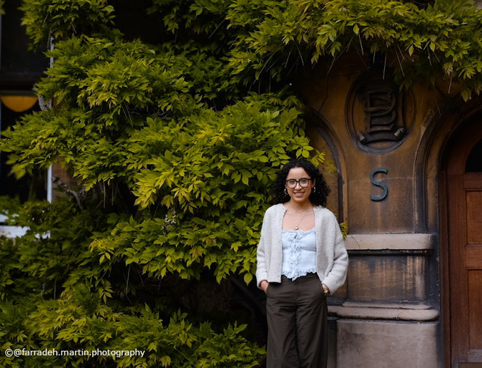Female Student leaning on side of building